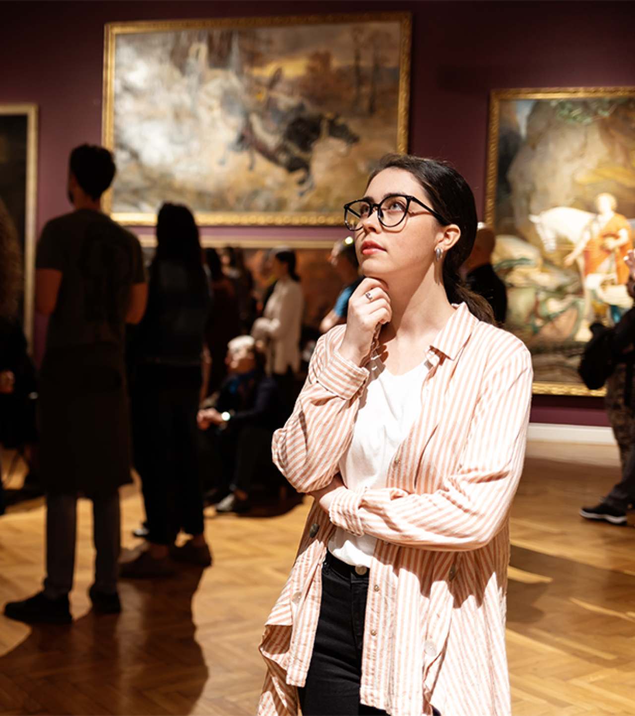 Young woman looking at paintings in a gallery.