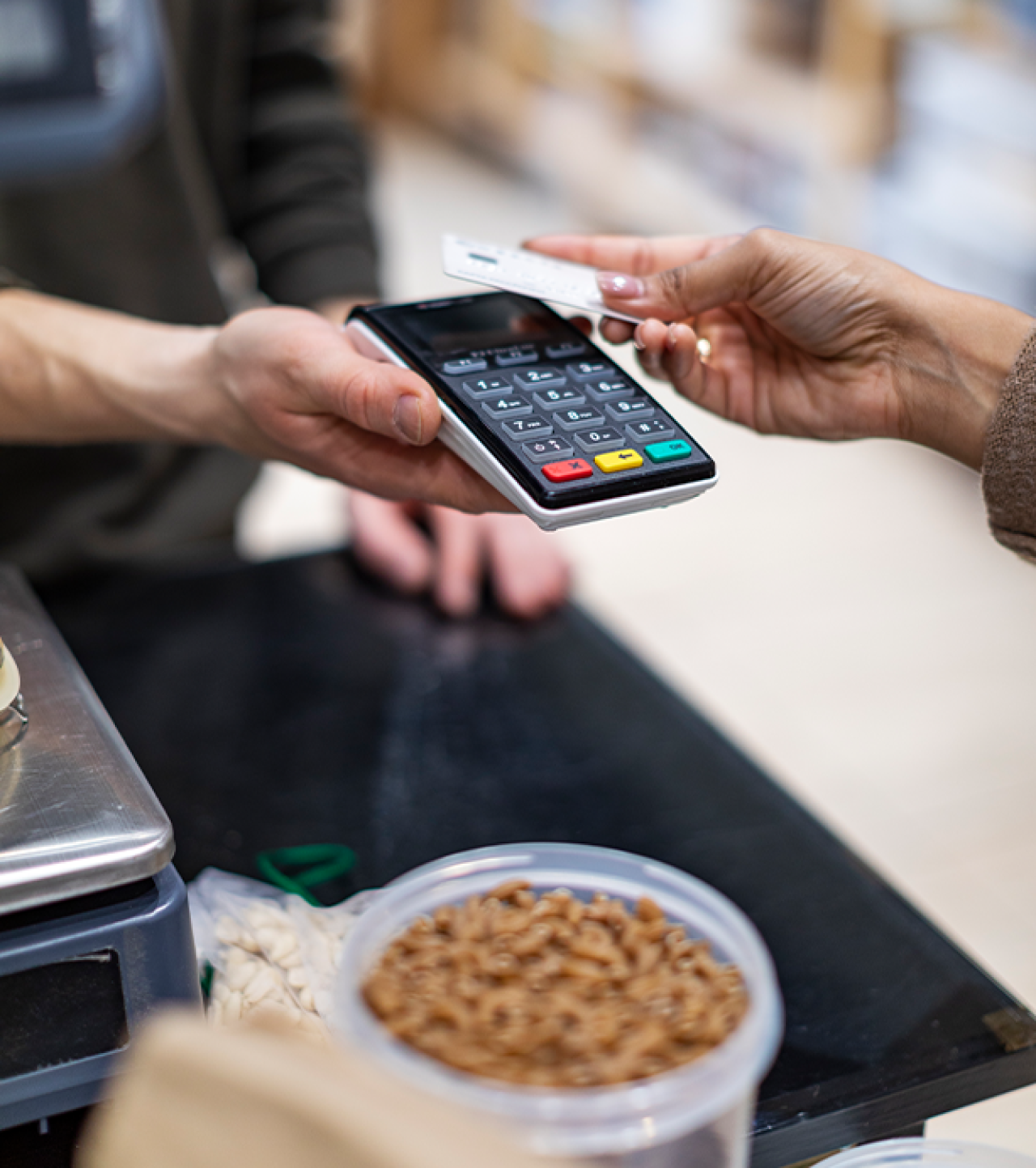 Womans hand making payment to a card machine.