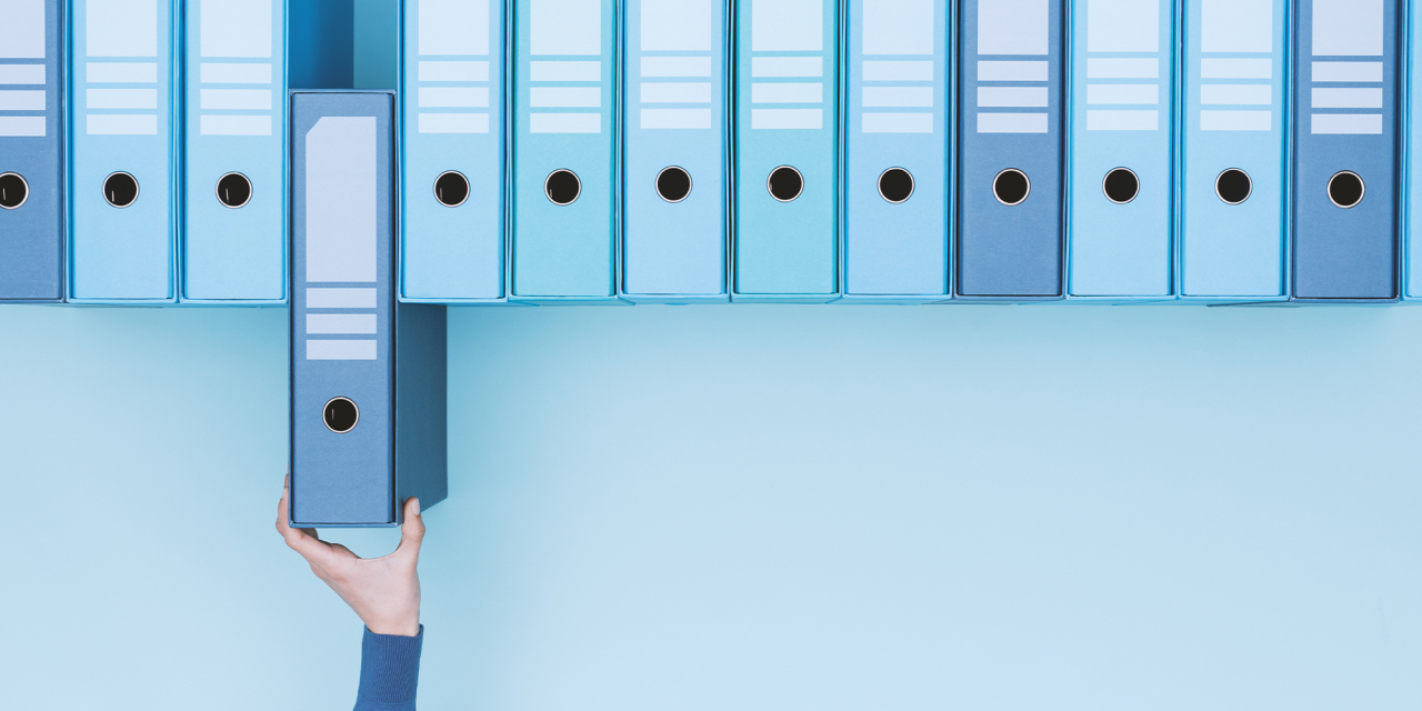 Person remoming a box file from a row.