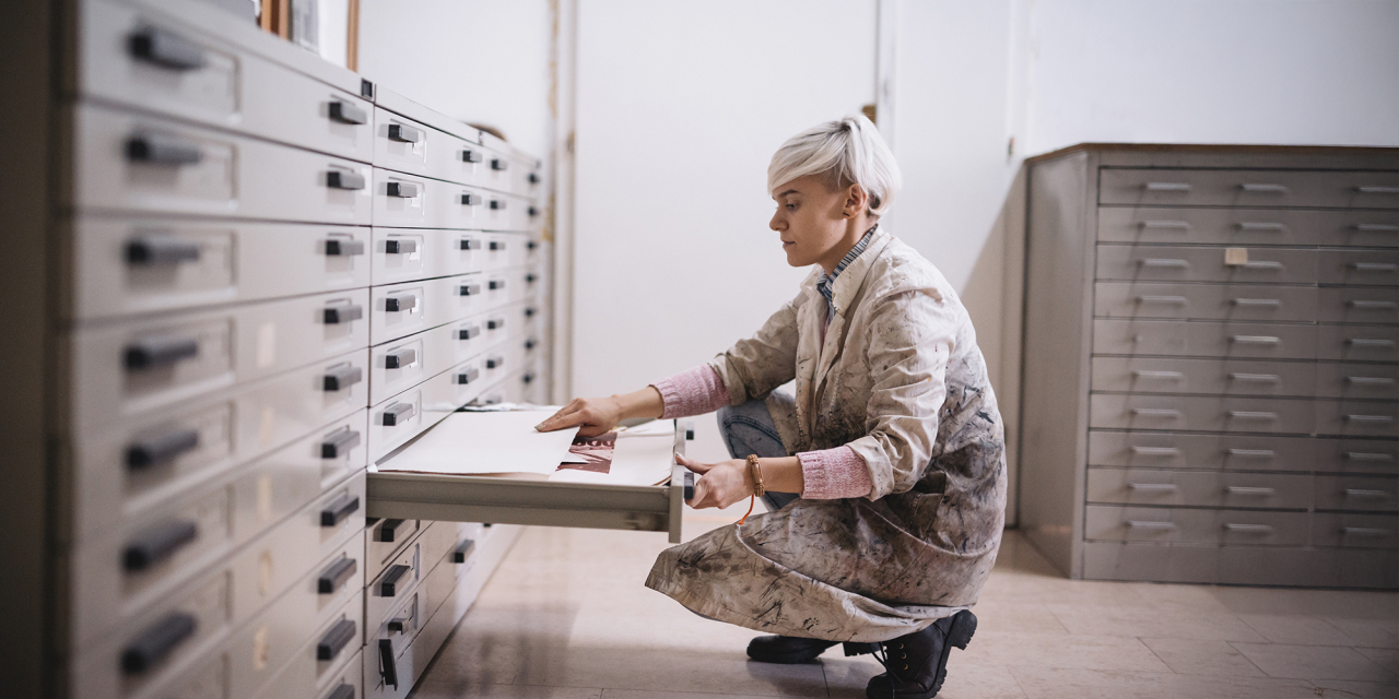 Woman crouching looking at heritage items securely stored.