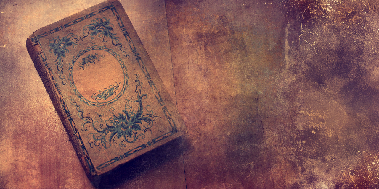 Old book with fine artwork to the cover on a table.