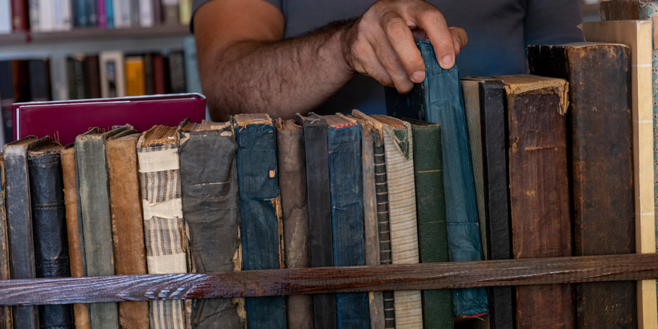 Damaged row of old books on a shelf awaiting repair.
