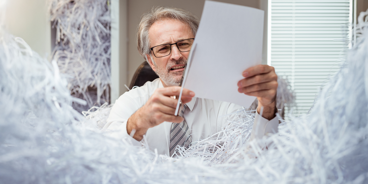 Man shredding documents with a pair of scissors.