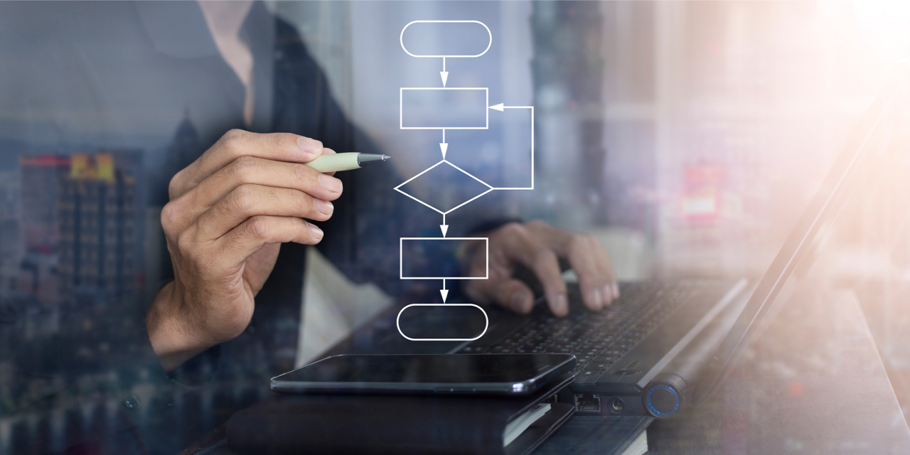 Hand holding pen working on computer with workflow overlay.